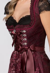 Burgundy fest dress with lace sleeves, corset front, silver hardware accents, and a satin ribbon belt. Intricate floral patterns on fabric.