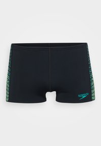 Fekete úszónadrág, testhez simuló fazonnal, zöld és kék geometriai mintázattal az oldalán, valamint egy kis "Speedo" logóval az elején.