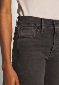 Donkergrijze jeans van denim, met een typische 5-pocketontwerp, een gestructureerde look en een middenhoogte tailleband. Het stiksel is zichtbaar.