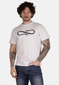T-shirt in cotone bianco con una grafica di un serpente nero e il simbolo dell'infinito sul davanti. Maniche corte, collo rotondo e vestibilità rilassata.