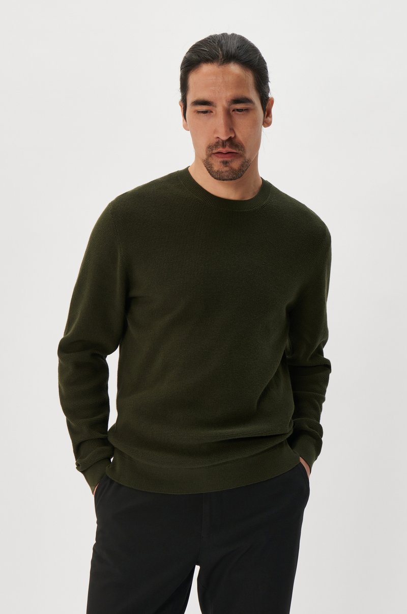 Dark green knitted sweater with a crew neckline and long sleeves, featuring a textured pattern and ribbed cuffs and hem.