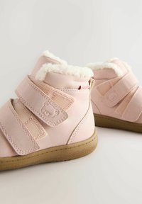 Rosa syntetiska stövlar med fluffigt foder, utrustade med två kardborreband, björnfacedetaljer och gummisulor med texturerat grepp.