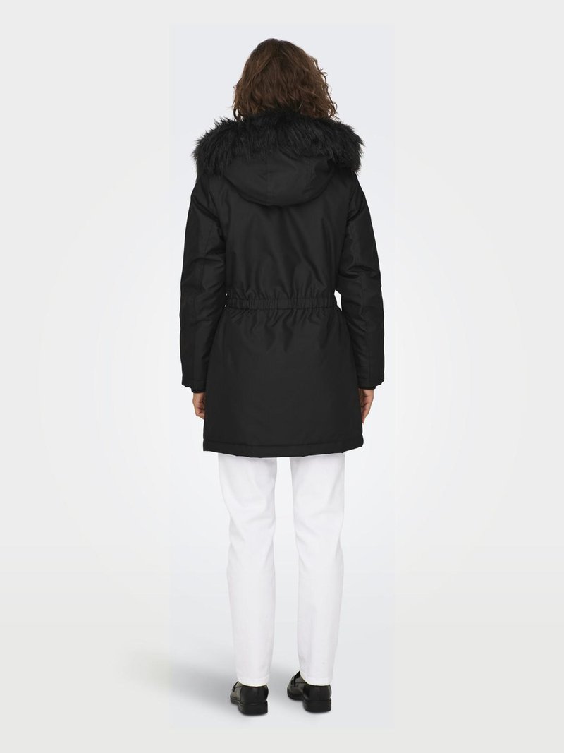 Parka noire avec une capuche en fourrure, taille à cordon de serrage et manches longues. Portée sur un pantalon blanc, montrant une texture lisse et une coupe décontractée.