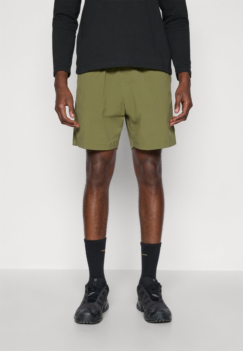 Olive green shorts made of lightweight fabric, featuring a relaxed fit and straight cut. Paired with black socks and athletic shoes.