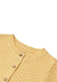 Kollane kootud kardigan ümarate kaelustega ja puidust nööpidega, millel on pehmel kangal tekstuurse avatud töö mustriga.