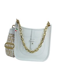 White leather handbag with a textured surface, gold chain handle, and a patterned fabric strap featuring a geometric design in beige.
