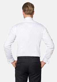 Biała koszula z długim rękawem, gładka w dotyku, z klasycznym kołnierzykiem i mankietami na guziki. Noszona z czarnymi spodniami, prezentując minimalistyczny design.