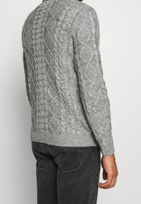 Pull gris à manches longues en maille torsadée avec un motif texturé en formes de losanges, coutures côtelées aux poignets et à l'ourlet. Confectionné en maille épaisse pour assurer la chaleur.