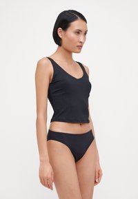 Black ribbed crop tank top with a V-neck and thin straps, paired with matching bikini bottoms. Smooth texture, minimalist design.