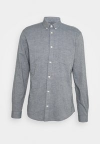 Camisa de botón de manga larga gris con un bolsillo en el pecho y cuello abotonado, exhibida sobre un fondo blanco.