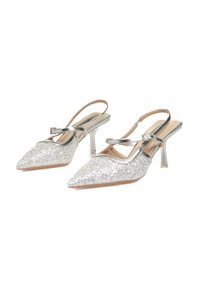 Tacones slingback plateados brillantes con punta afilada, acentos metálicos y un tacón bloque translúcido. Presenta una delicada correa en el tobillo.