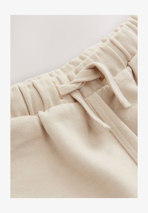 Pantalones deportivos de algodón color crema con un acabado texturizado, presentan una cintura fruncida y un cordón para un ajuste ajustable.
