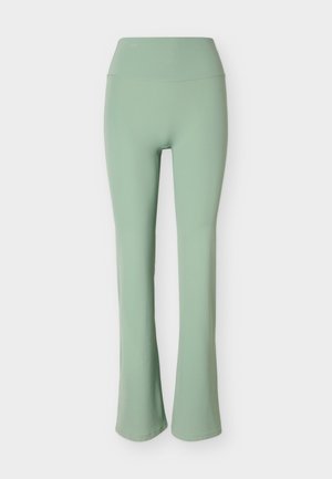 Pantalon extensible vert clair à taille haute avec une partie supérieure ajustée et des jambes légèrement évasées, sur un fond uni.