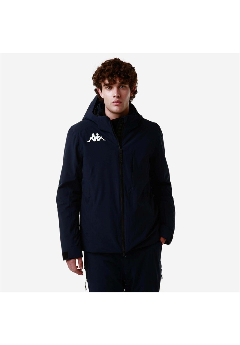 Giacca con cappuccio blu navy con cerniera frontale, tasche laterali e un logo bianco sul petto. Realizzata in un materiale liscio e resistente agli agenti atmosferici.