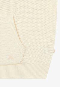 Sweter z dzianiny w kolorze kremowym z teksturowanym wzorem, z ściągaczami na mankietach i przednią kieszenią. Posiada małą metkę na kieszeni.