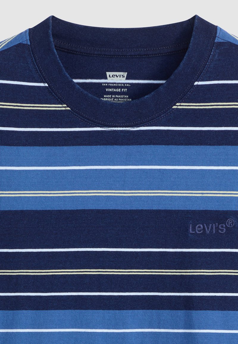 Granatowa koszulka w paski w różnych odcieniach niebieskiego z cienkimi białymi i żółtymi liniami. Posiada okrągły dekolt oraz haftowane logo Levi's.