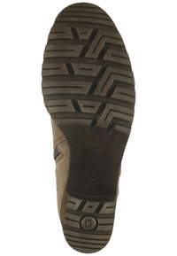 Zapato de ante marrón con suela de goma negra. La suela presenta un patrón texturizado para mejorar el agarre, con una marca en el lateral y un cierre de cremallera en la parte superior.