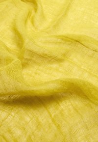 Żółta gaza o przezroczystej, teksturowanej powierzchni. Materiał wydaje się lekki i starannie tkany, co tworzy miękki efekt drapowania.