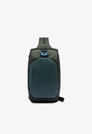 Mochila verde con un exterior texturizado, un panel frontal verde oscuro elegante, detalles negros, una cremallera superior y un adorno azul metálico.