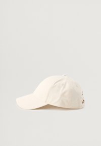 Gorra de béisbol de algodón beige con visera curva, correa ajustable en la parte posterior y un detalle de logo en el lateral. Textura suave, forma estructurada.