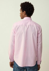 Cămașă roz cu dungi, cu mâneci lungi, manșete cu nasturi, guler și tiv drept. Fabricată dintr-un material neted; textură subtilă și model vertical.