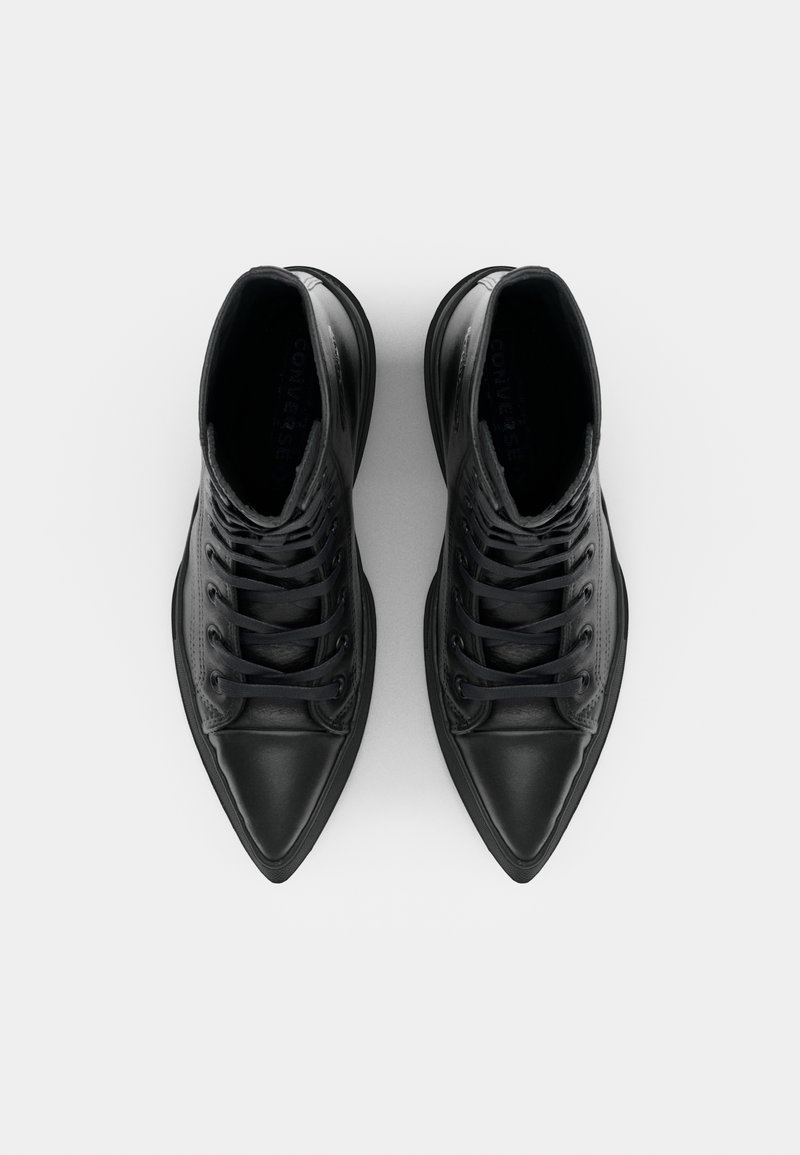 Bottines noires à bout pointu, en cuir avec semelle plate en caoutchouc. Présente des œillets et des lacets.