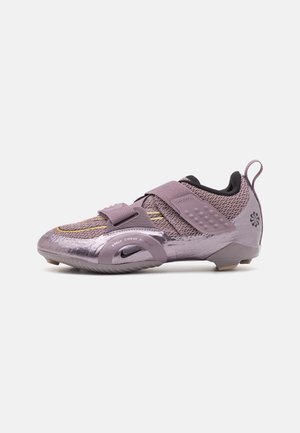 Lilla cykelsko med mesh-overdel, to brede stropper, gummibeskyttelse ved tåen og lille sort Nike-logo på siden.