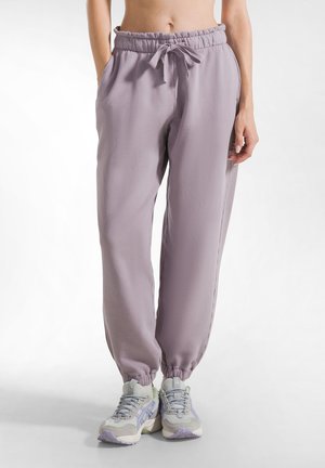 Pantaloni jogging lavanda con vita regolabile e polsini a tapered, dotati di tasche laterali. Realizzati in tessuto morbido e leggero con una trama liscia.