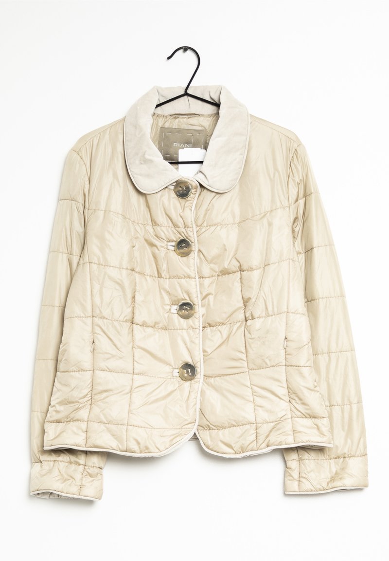 Veste matelassée beige avec de gros boutons, col arrondi et manches longues suspendue sur un cintre noir.