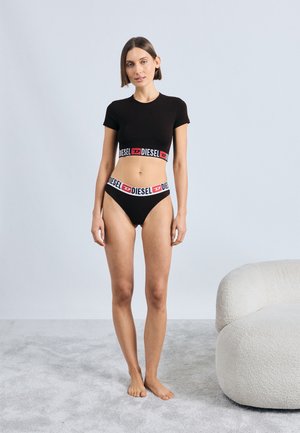 Μαύρο κοντό μπλουζάκι και ταιριαστό μπικίνι, με ελαστική ζώνη που φέρει λογότυπο σε λευκό και κόκκινο. Απαλή ύφανση, εφαρμοστό σχέδιο.
