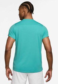 Camiseta atlética de manga corta en color turquesa con una textura suave, presenta un diseño sencillo y un detalle en la costura trasera. Diseñada para ropa activa.