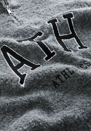 Hallhalli halli, mis on poolsahtel, sisaldab musti brodeeritud tähti "ATH" ja õrna tekstuuri. Pehme, mugav kangas, millel on veidi kulunud välimus.