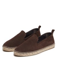 Chaussures slip-on en suède marron avec une semelle en corde de jute et des inserts latéraux élastiques, présentant une texture lisse et un design à bout arrondi.