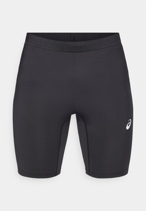 Shorts de sport noirs en tissu extensible ; caractéristiques d'une texture lisse, de coutures plates et d'un petit logo blanc sur le côté gauche.