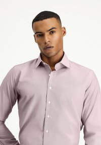 Camicetta rosa chiaro con colletto classico, maniche lunghe e bottoni bianchi, realizzata in tessuto morbido.