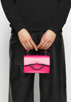 Piccola borsa in pelle rosa con manico a catena, caratterizzata da una chiusura a pattina e un design minimalista. Il logo è visibile al centro in basso.