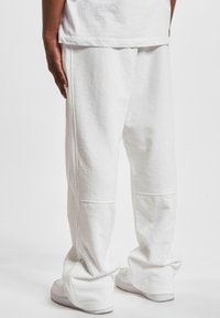 Hvide sweatpants i bomuld med løs pasform, der har sidesyninger og en blød tekstur, parret med hvide sneakers.