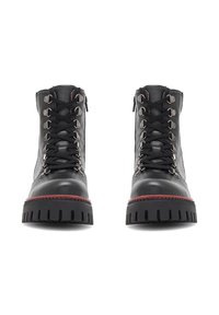 Černé kožené kotníkové boty s kovovými očky, kontrastními červenými akcenty na podešvi a drsným vzorem pro lepší trakci.