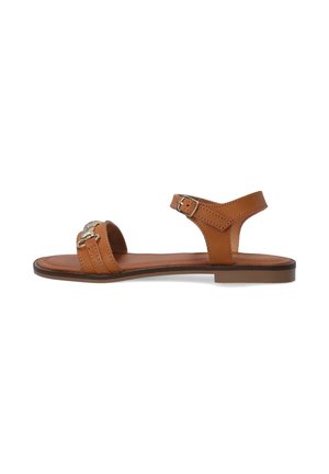 Sandale aus braunem Leder mit flacher Sohle, verstellbarem Knöchelriemen und dekorativen Metallakzenten auf dem Obermaterial. Glatte Oberfläche und offenes Design.