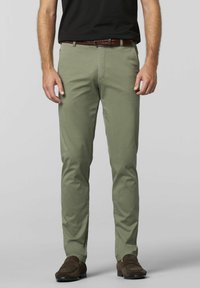 Licht olijfgroene broek van een gladde stof, met zakken en een slim-fit ontwerp, gecombineerd met een gevlochten bruine leren riem en donkere schoenen.