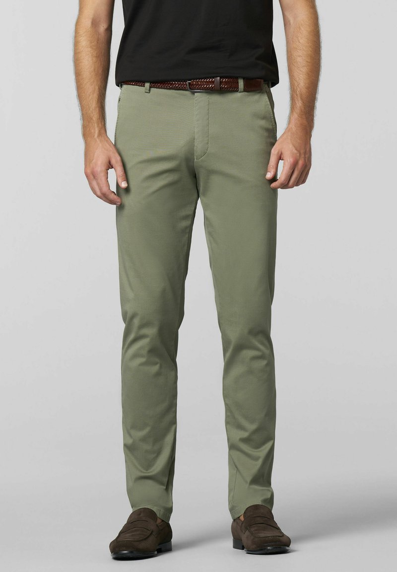 Licht olijfgroene broek van een gladde stof, met zakken en een slim-fit ontwerp, gecombineerd met een gevlochten bruine leren riem en donkere schoenen.