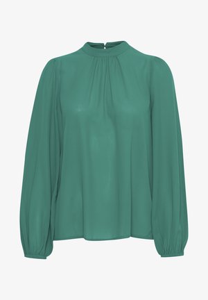 Zaļa, ar garām piedurknēm, blūze ar augstu apkakli, ar krokotiem detaļām un savilktiem piedurkņu galiem. Audums ir gluds un viegls.