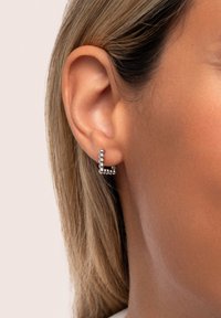 Silberner Ohrcuff mit einer strukturierten, perlenartigen Gestaltung in geometrischer Form, getragen am äußeren Ohr auf heller Haut.