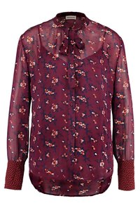 Blusa trasparente bordeaux con motivo floreale in arancione, bianco e blu. Presenta un laccio al collo, chiusura a bottoni e polsini a fantasia. Maniche lunghe.