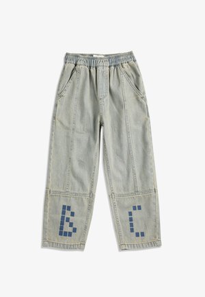 Pantalon en denim bleu clair avec taille élastique et poches avant, présentant des motifs de lettres bleues pixélisées près du bas de chaque jambe.