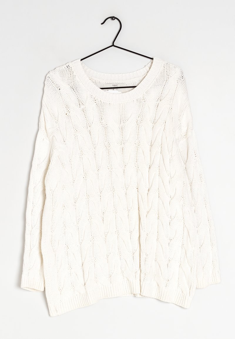 Un pull en tricot blanc avec un motif en relief, un col rond, des manches longues et des poignets et un ourlet côtelés, suspendu à un crochet noir.