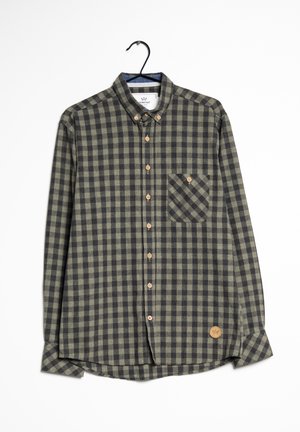 Camicia a quadri verde e nera con bottoni, maniche lunghe, taschino sul petto, bottoni in legno e toppa con logo sull'orlo.