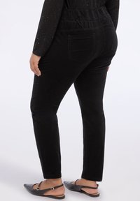 Pantalones negros con cintura elástica, corte ajustado y bolsillos traseros. Textura suave, que combina comodidad y funcionalidad.