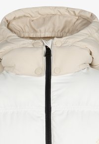 Puffer jacket with a beige hood, white body, black zipper front, and snap buttons. Features a quilted texture and a high collar design.