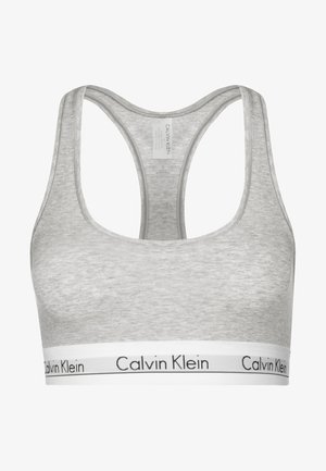 Siva bombažna športna modrček z širokim belim pasom, na katerem je v črnem tisku napisano "Calvin Klein". Ima dizajn s hrbtnim izrezom in gladko teksturo.
